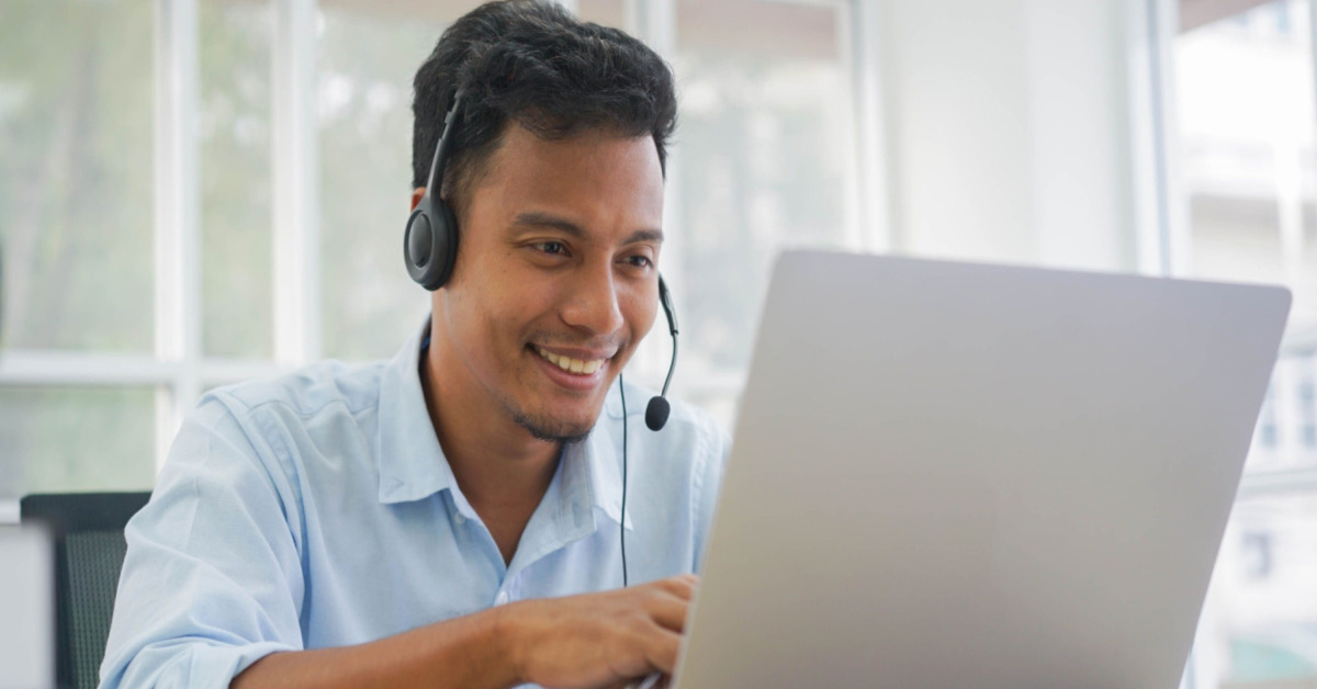Latino male agent with headphones and computer